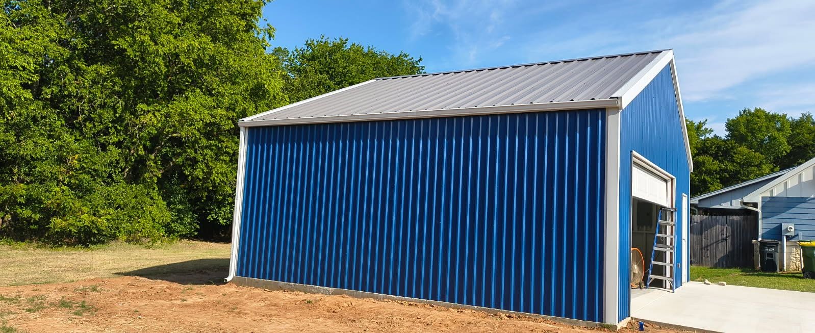 Blue metal workshop with a light gutter along the roof edge and a downspout at the corner