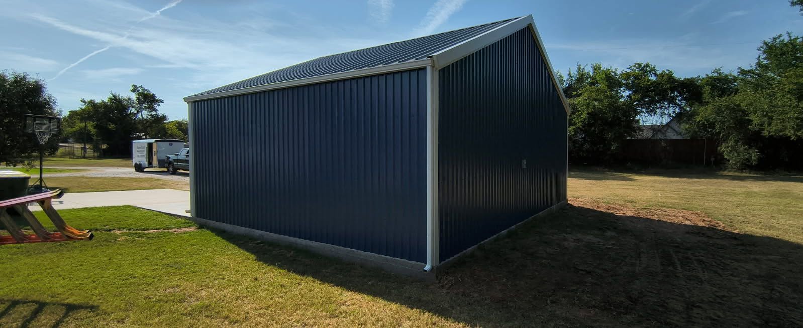 Dark metal building with light-colored roofline trim, gutter and corner downspout